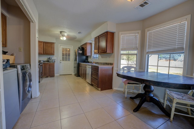 kitchen with appliances with stainless steel finishes, washing machine and dryer, a textured ceiling, and light tile patterned floors