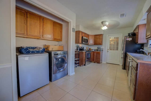 laundry area featuring light tile patterned floors, sink, independent washer and dryer, and a textured ceiling