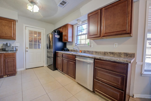 kitchen with sink, a textured ceiling, light tile patterned floors, ceiling fan, and stainless steel appliances