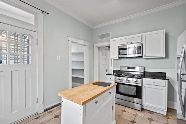 kitchen with crown molding, butcher block counters, stainless steel appliances, a center island, and white cabinets