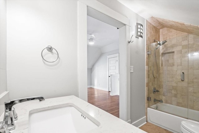 full bathroom featuring toilet, vanity, shower / bath combination with glass door, and vaulted ceiling