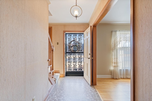 entryway featuring ornamental molding, wood finished floors, baseboards, and stairs