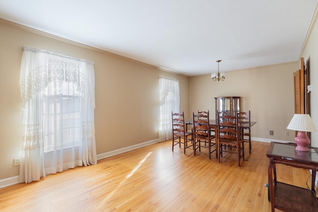 dining area with light wood-style floors, baseboards, a chandelier, and ornamental molding