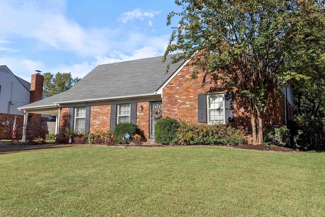 view of front of house featuring brick siding, a front lawn, and roof with shingles