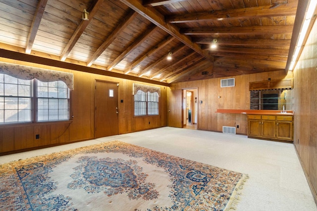 living area featuring visible vents, wooden walls, and lofted ceiling with beams