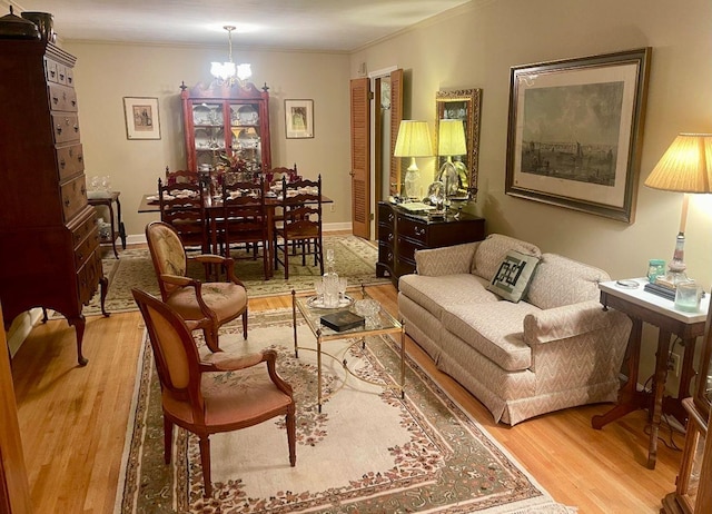 living area with ornamental molding, light wood finished floors, baseboards, and an inviting chandelier