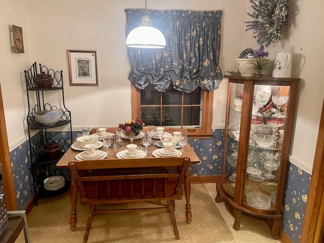 dining area featuring a wainscoted wall and wallpapered walls