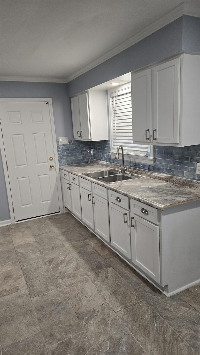 kitchen featuring white cabinetry, sink, backsplash, and ornamental molding