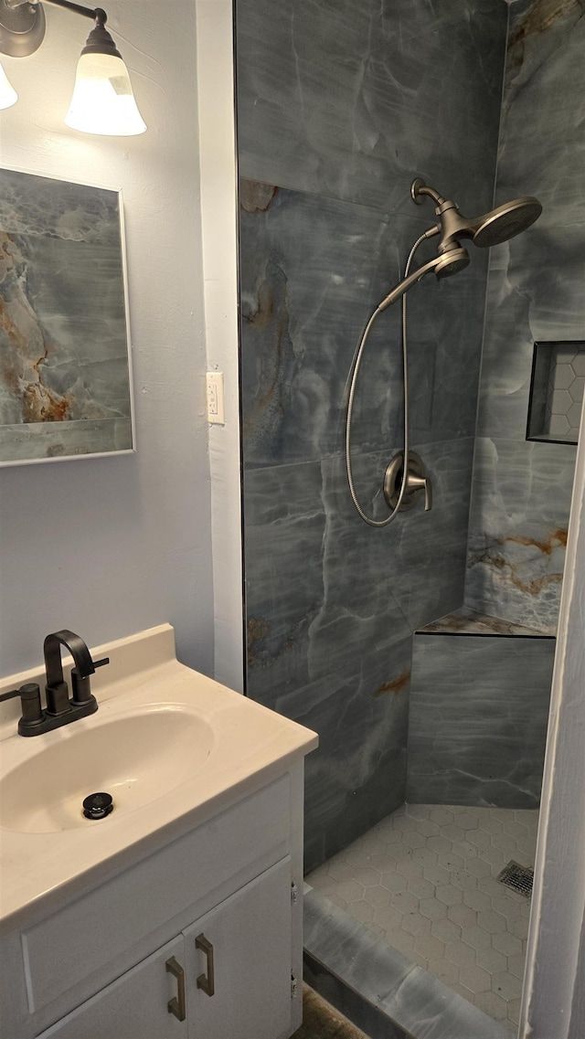 bathroom featuring tiled shower and vanity