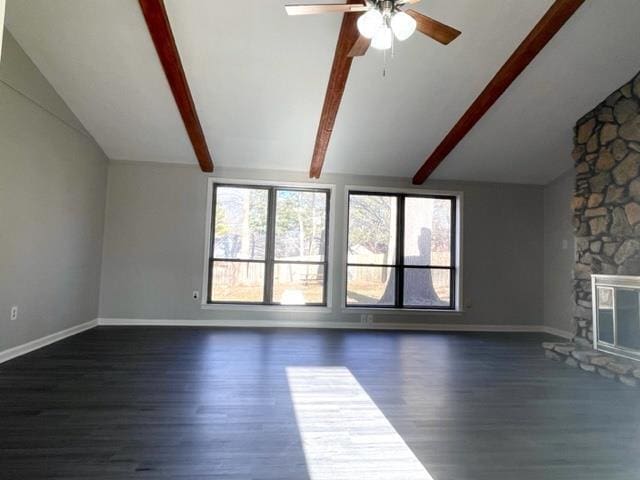 unfurnished living room with ceiling fan, a stone fireplace, vaulted ceiling with beams, and dark hardwood / wood-style floors