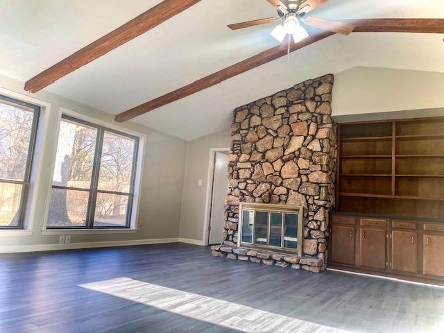 unfurnished living room with dark hardwood / wood-style floors, a fireplace, and vaulted ceiling with beams