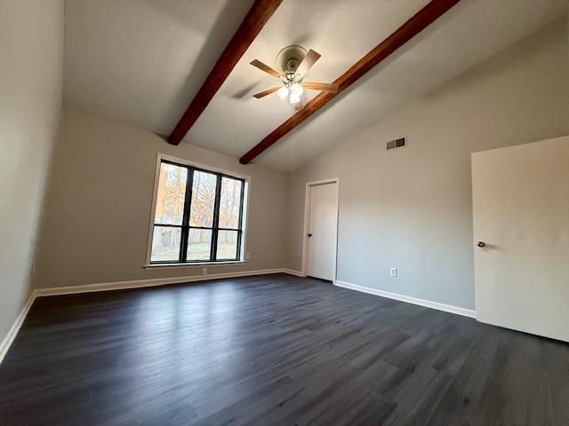 empty room featuring dark wood-type flooring, vaulted ceiling with beams, and ceiling fan