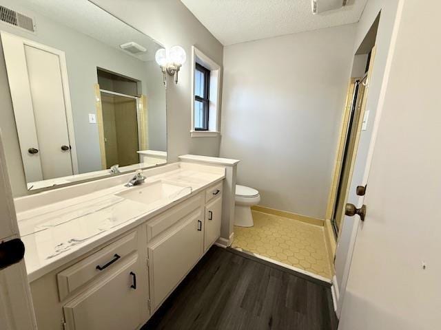 bathroom featuring toilet, an enclosed shower, a textured ceiling, vanity, and hardwood / wood-style flooring