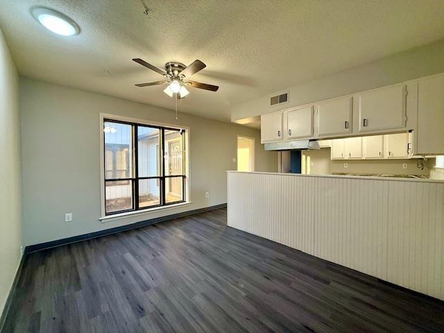 kitchen featuring ceiling fan, dark wood-type flooring, white cabinets, and a textured ceiling