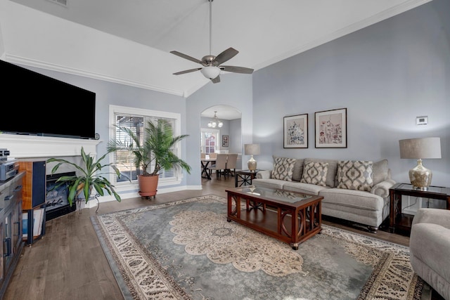 living room with dark wood-type flooring, ceiling fan with notable chandelier, and high vaulted ceiling