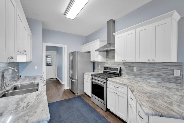 kitchen with sink, light stone counters, white cabinets, stainless steel appliances, and wall chimney range hood