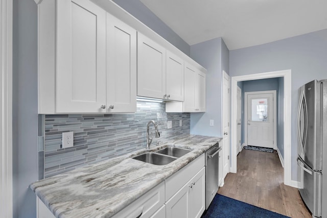 kitchen with white cabinetry, stainless steel appliances, light stone countertops, and sink