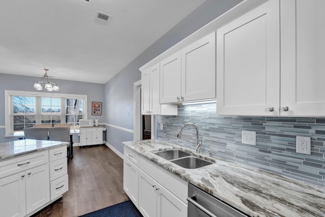 kitchen with sink, white cabinetry, hanging light fixtures, light stone counters, and decorative backsplash