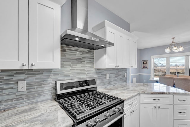 kitchen featuring white cabinets, light stone countertops, gas stove, and wall chimney exhaust hood