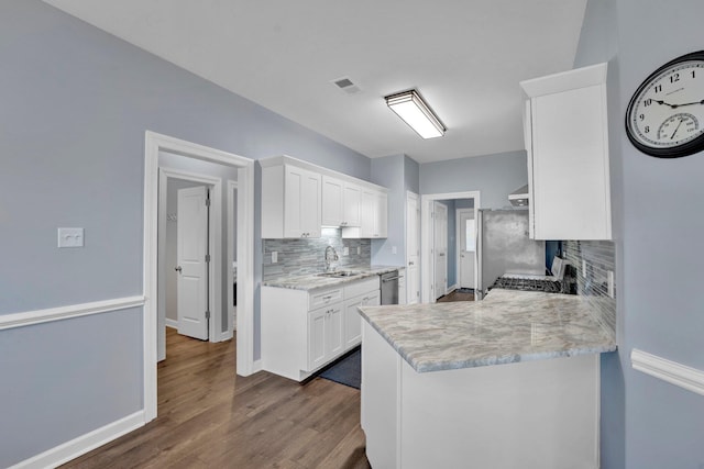 kitchen with sink, appliances with stainless steel finishes, white cabinets, dark hardwood / wood-style flooring, and decorative backsplash