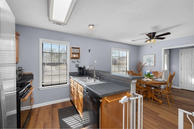 kitchen featuring plenty of natural light, sink, dark hardwood / wood-style flooring, and black appliances