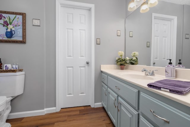 bathroom featuring wood-type flooring, vanity, and toilet