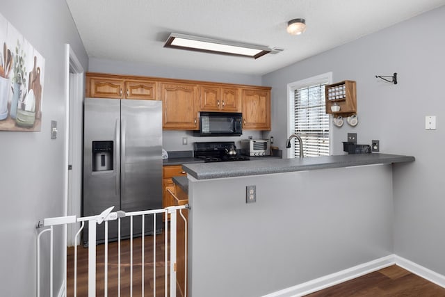 kitchen featuring range, a textured ceiling, dark hardwood / wood-style flooring, stainless steel fridge, and kitchen peninsula