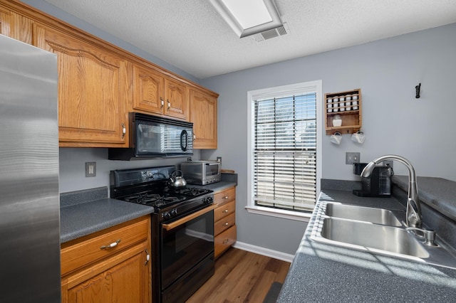 kitchen featuring dark wood-type flooring, sink, a textured ceiling, and black appliances