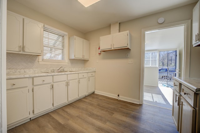 kitchen with hardwood / wood-style flooring, sink, tasteful backsplash, and white cabinets