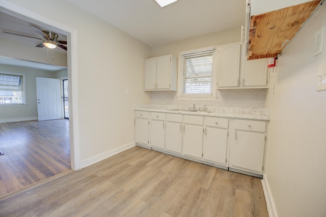 kitchen featuring sink, light hardwood / wood-style flooring, ceiling fan, white cabinetry, and decorative backsplash