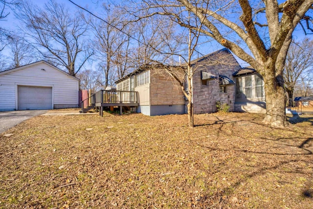 view of property exterior featuring a garage, an outdoor structure, and a deck