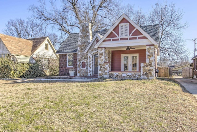 tudor house with a front yard, ceiling fan, and a porch