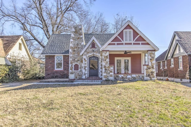 tudor house featuring ceiling fan and a front yard