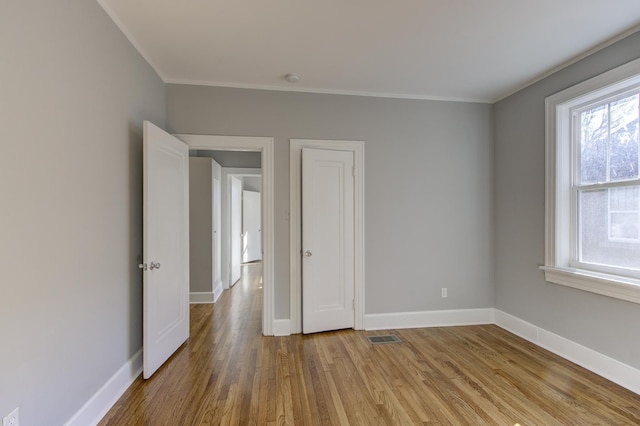 spare room with ornamental molding, plenty of natural light, and light hardwood / wood-style flooring