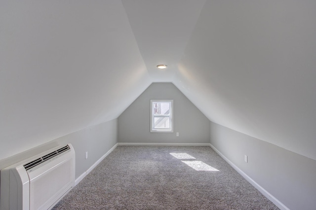 additional living space featuring vaulted ceiling, carpet floors, and a wall mounted air conditioner