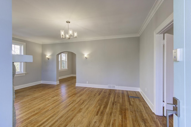 spare room featuring crown molding, a healthy amount of sunlight, hardwood / wood-style floors, and an inviting chandelier