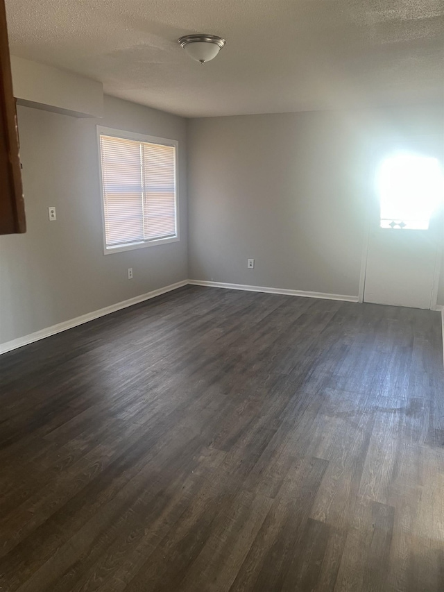 empty room with dark wood-type flooring and a textured ceiling