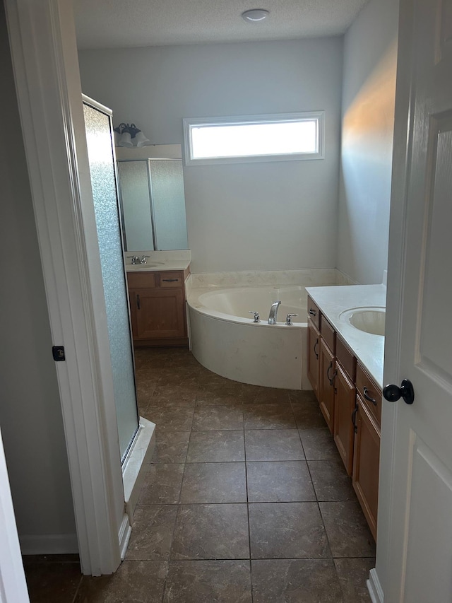 full bathroom with two vanities, a sink, a textured ceiling, and a bath