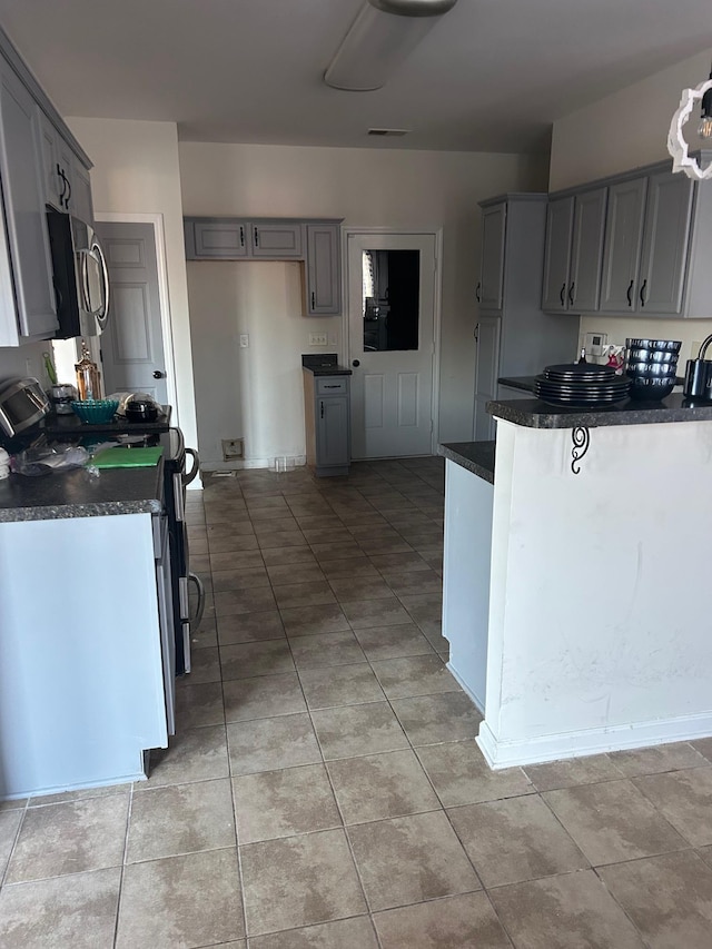 kitchen with visible vents, dark countertops, stainless steel appliances, gray cabinetry, and light tile patterned flooring