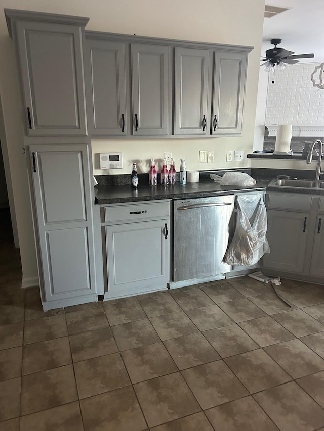 kitchen with dark countertops, dishwashing machine, ceiling fan, gray cabinetry, and a sink