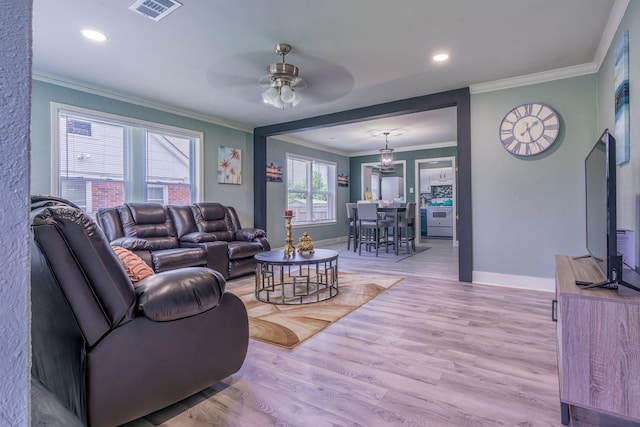 living room featuring ornamental molding, light hardwood / wood-style floors, and ceiling fan