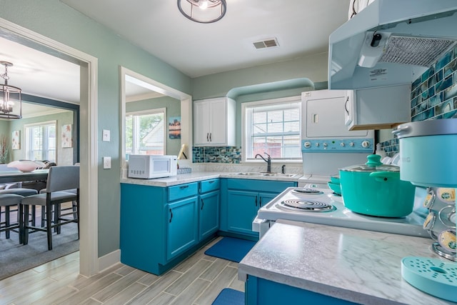 kitchen with sink, decorative backsplash, a notable chandelier, electric range, and blue cabinetry