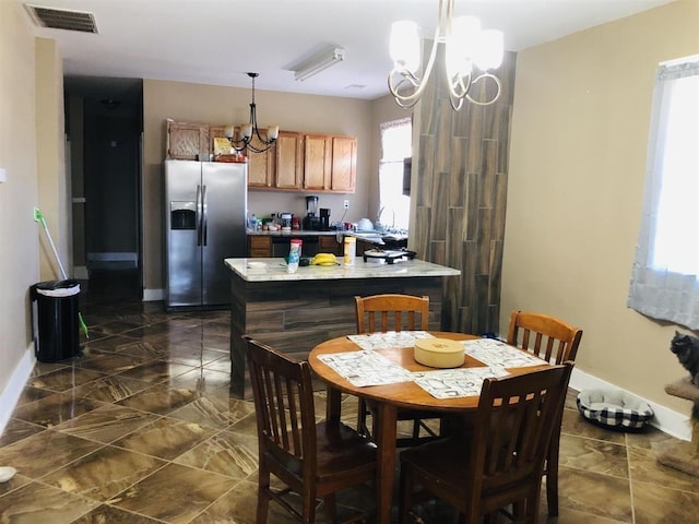 kitchen with hanging light fixtures, an inviting chandelier, and stainless steel fridge with ice dispenser