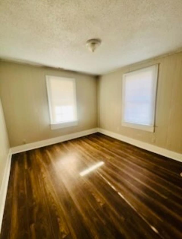 unfurnished room with a textured ceiling and dark hardwood / wood-style flooring