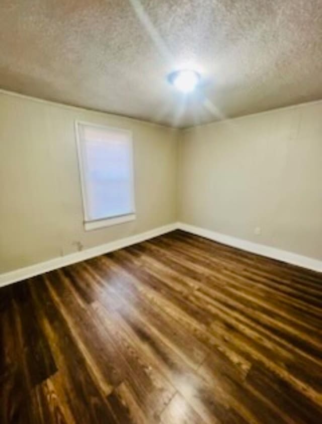 spare room with dark wood-type flooring and a textured ceiling