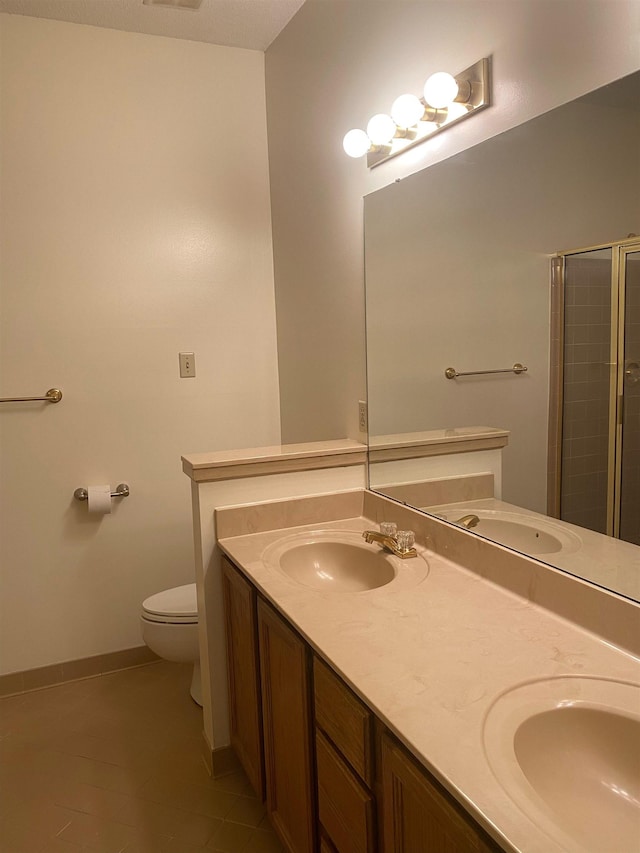 bathroom with tile patterned floors, toilet, a shower with shower door, and vanity