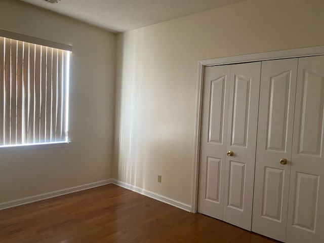 unfurnished bedroom featuring dark hardwood / wood-style flooring and a closet