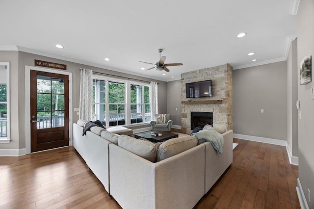 living room featuring ornamental molding, wood-type flooring, and a stone fireplace