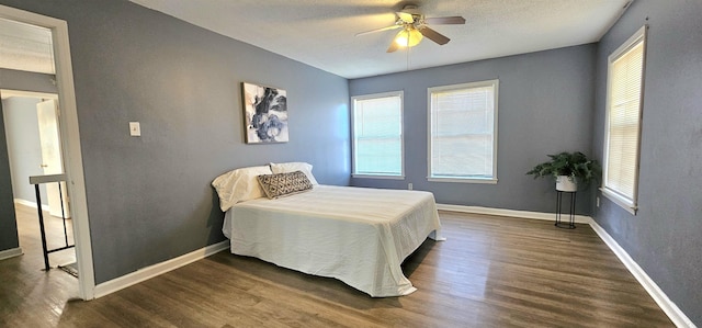 bedroom with a textured ceiling, dark wood-type flooring, and ceiling fan