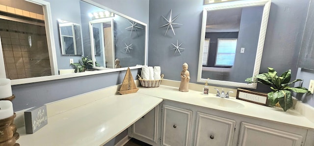 bathroom with tiled shower and vanity